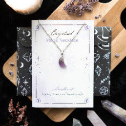 Crystal Moon necklace on a branded card with decorative elements on a wooden board.