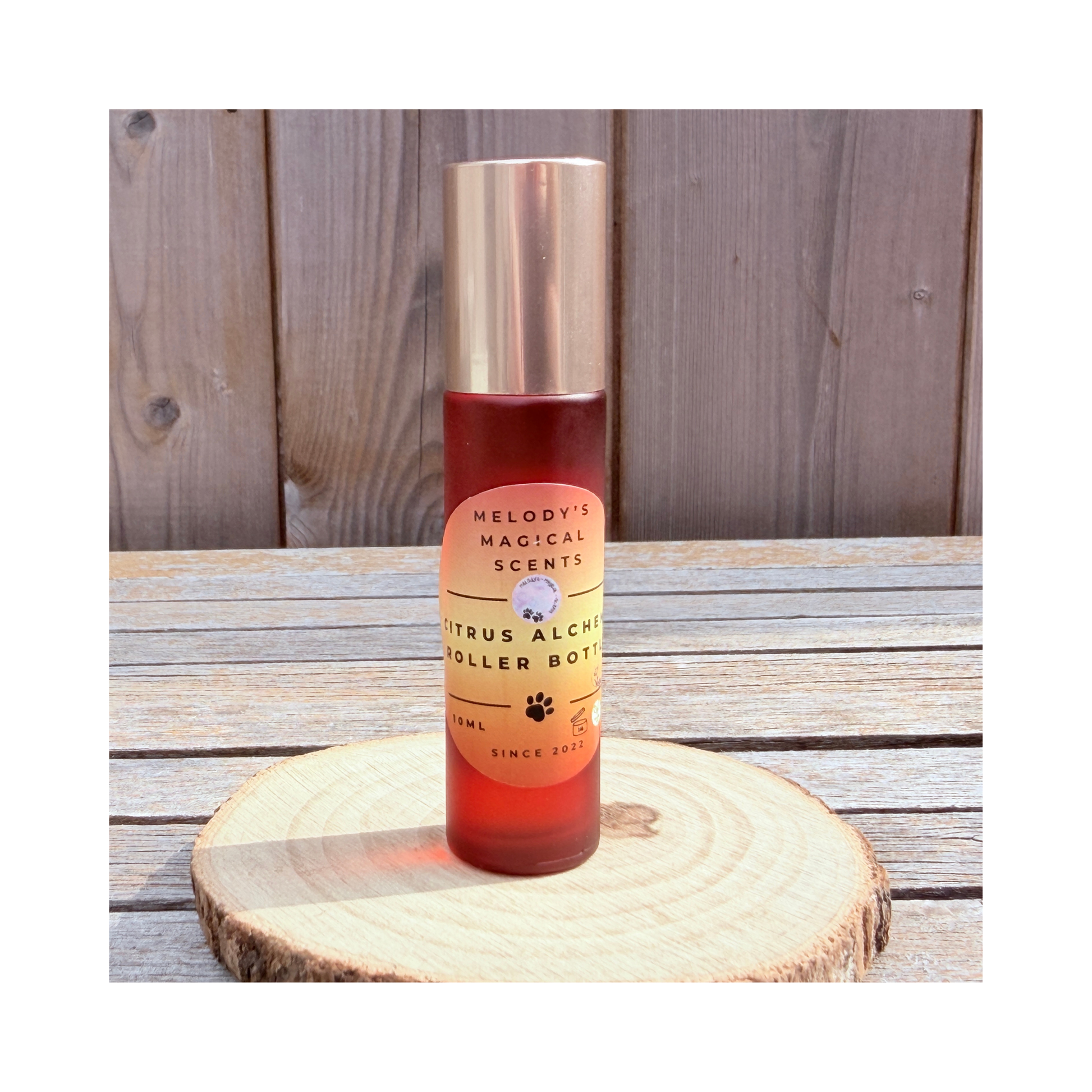 Roller bottle with gold cap and orange label on a wooden surface