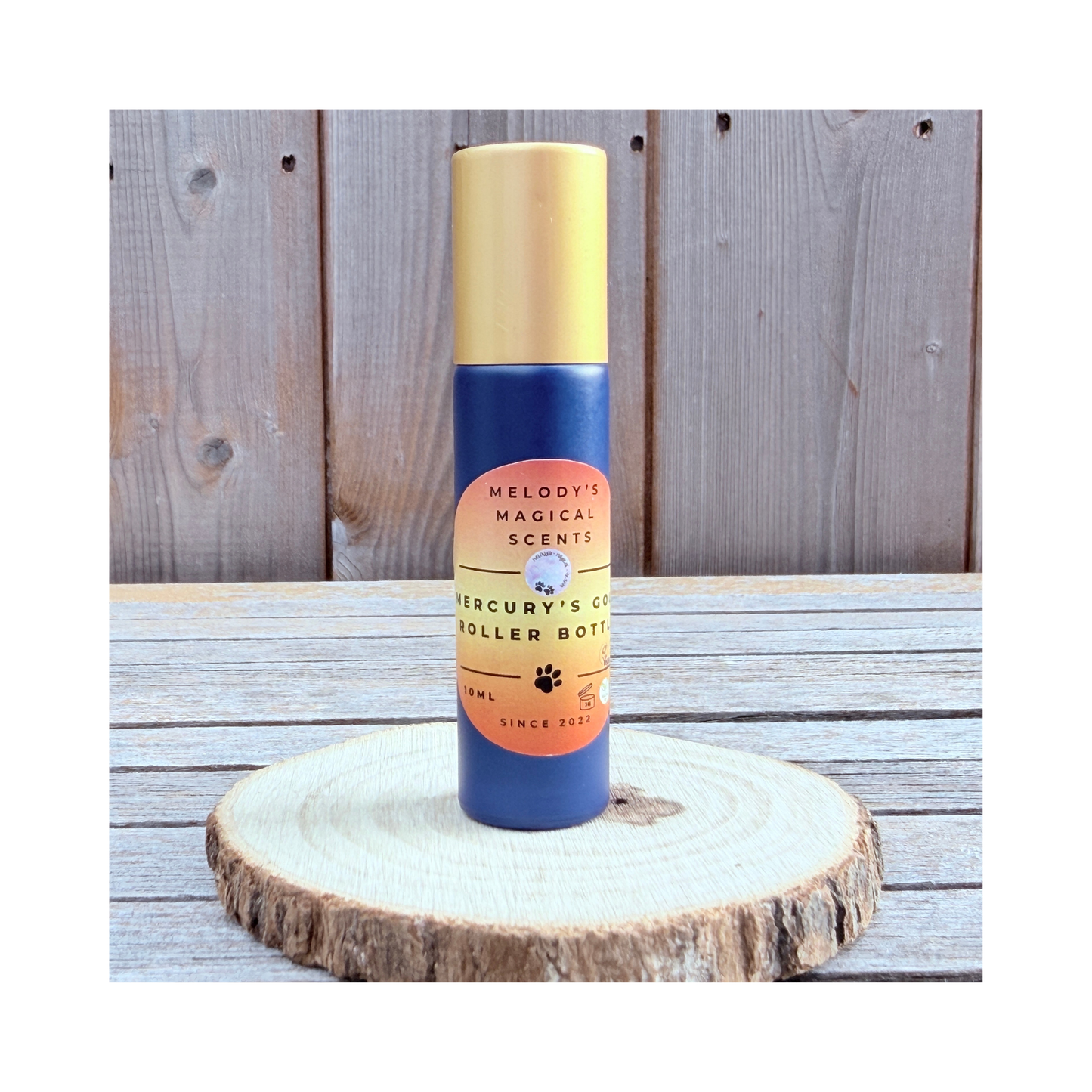 A dark blue roller bottle with the words "Mercury's Gold" standing on a wooden table