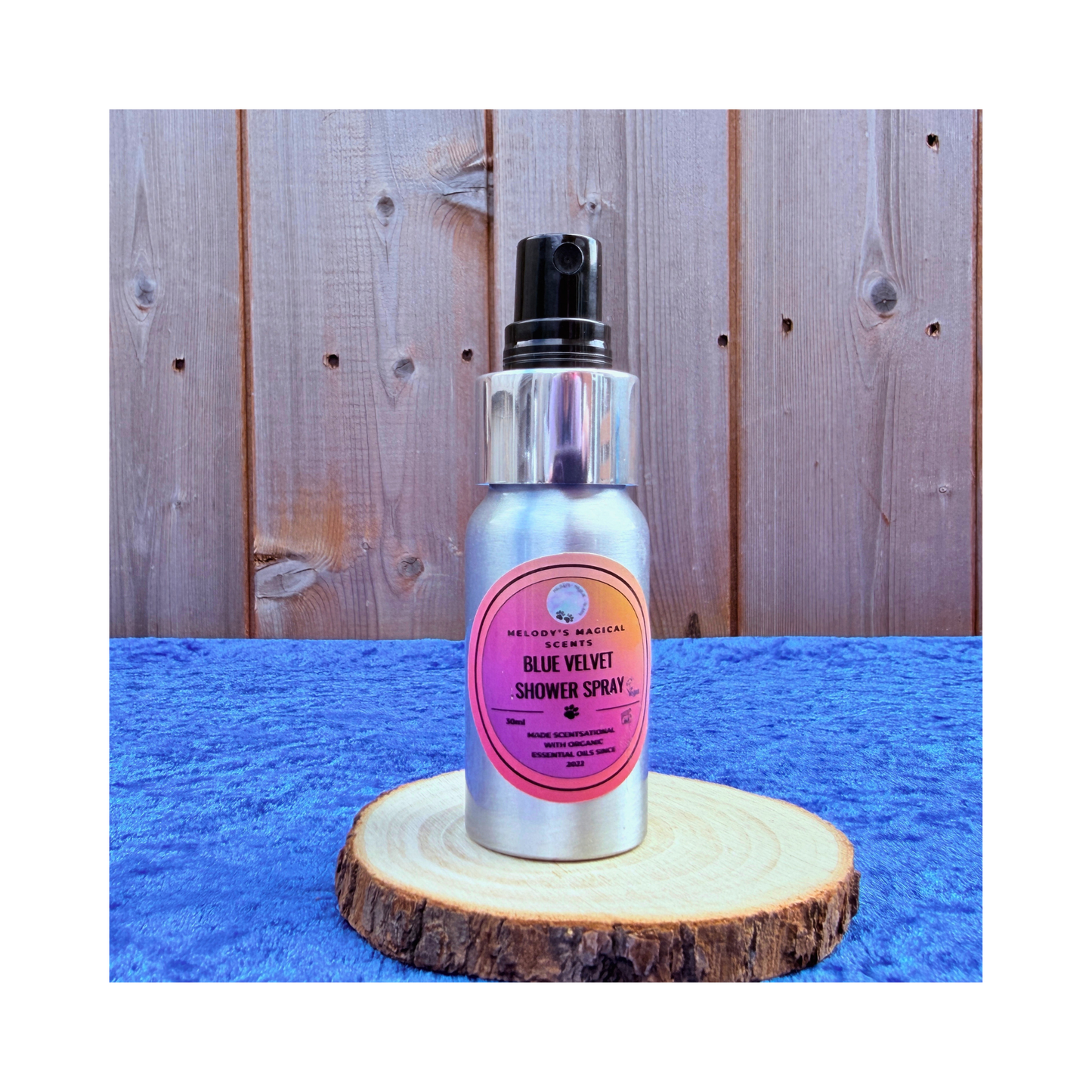 Silver shower spray bottle with pink label on a wooden platform against a wooden background
