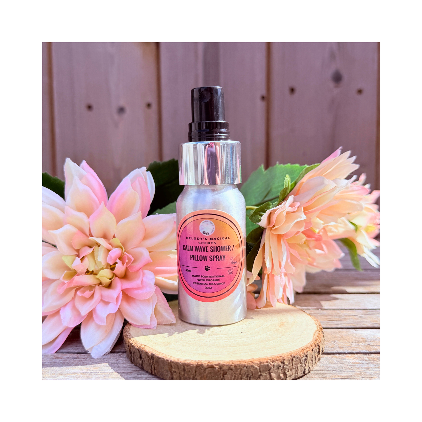 Bottle of 'Calm Wave Shower & Pillow Spray' with pink flowers on a wooden surface