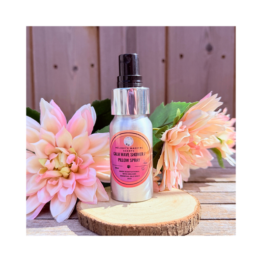 Bottle of 'Calm Wave Shower & Pillow Spray' with pink flowers on a wooden surface