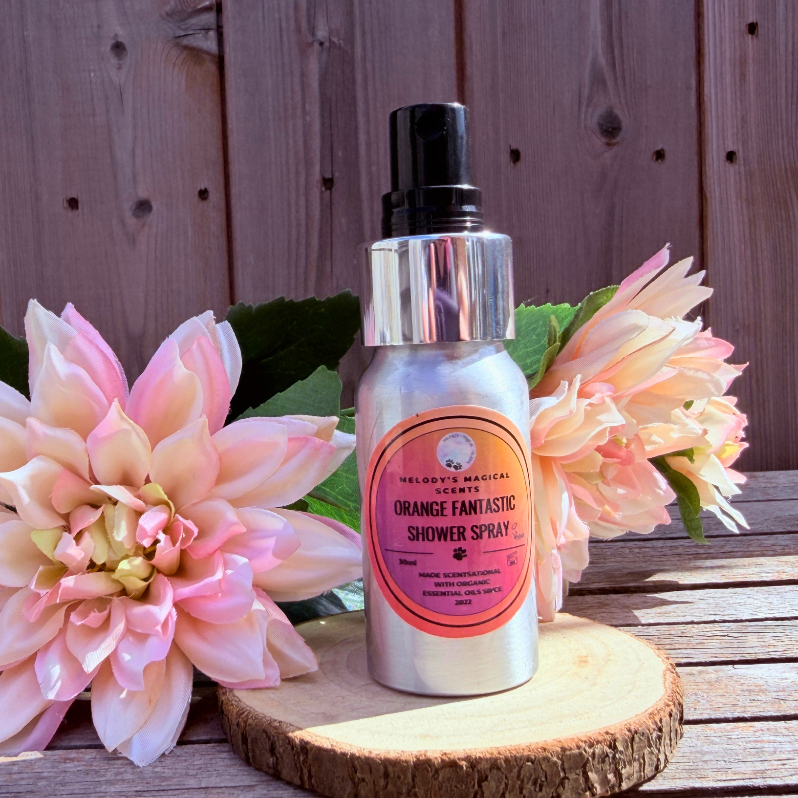 Shower spray bottle with pink label on a wooden surface with flowers